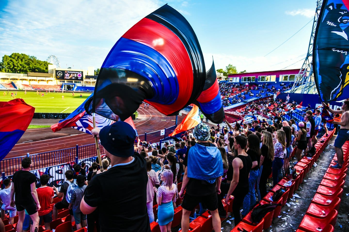 Spectators wave colorful flags at a crowded football stadium.
